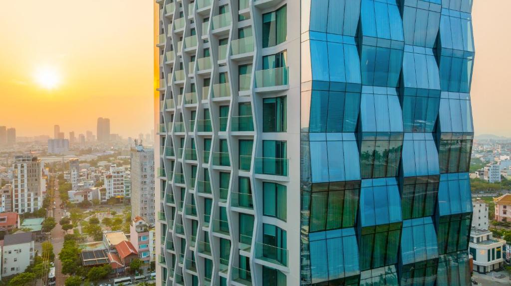 a tall building with the sunset in the background at Awaken Da Nang Hotel in Danang