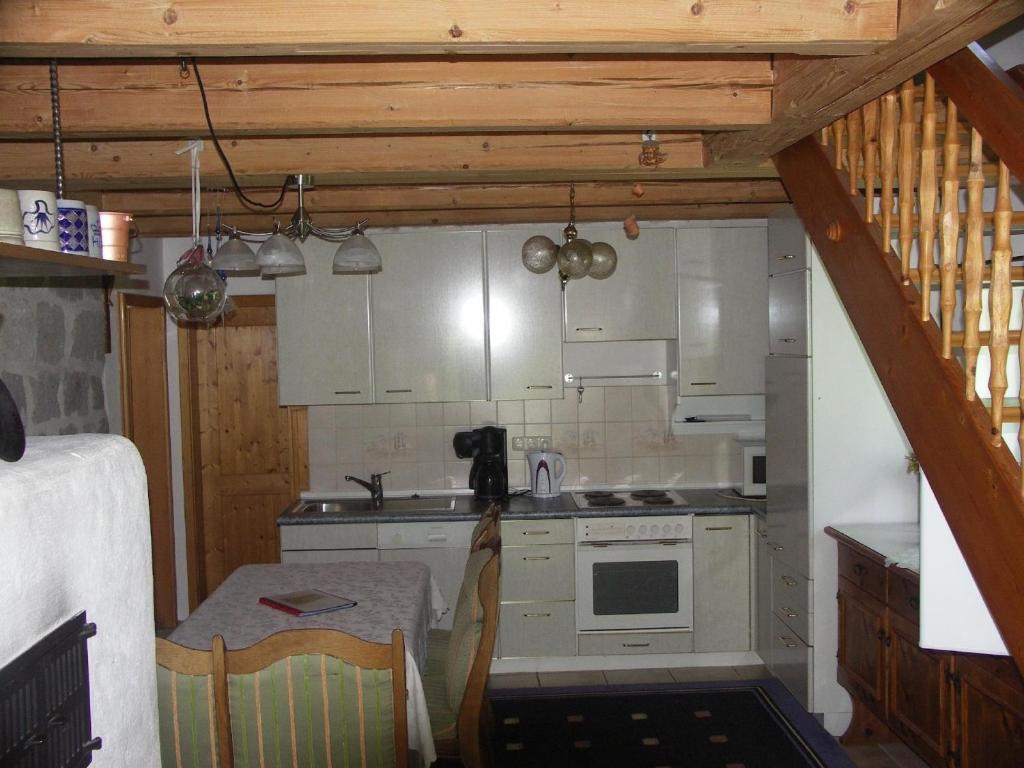 una pequeña cocina con armarios blancos y una mesa en Ferienwohnung im Bayerischen Wald für 5 Personen, en Kollnburg