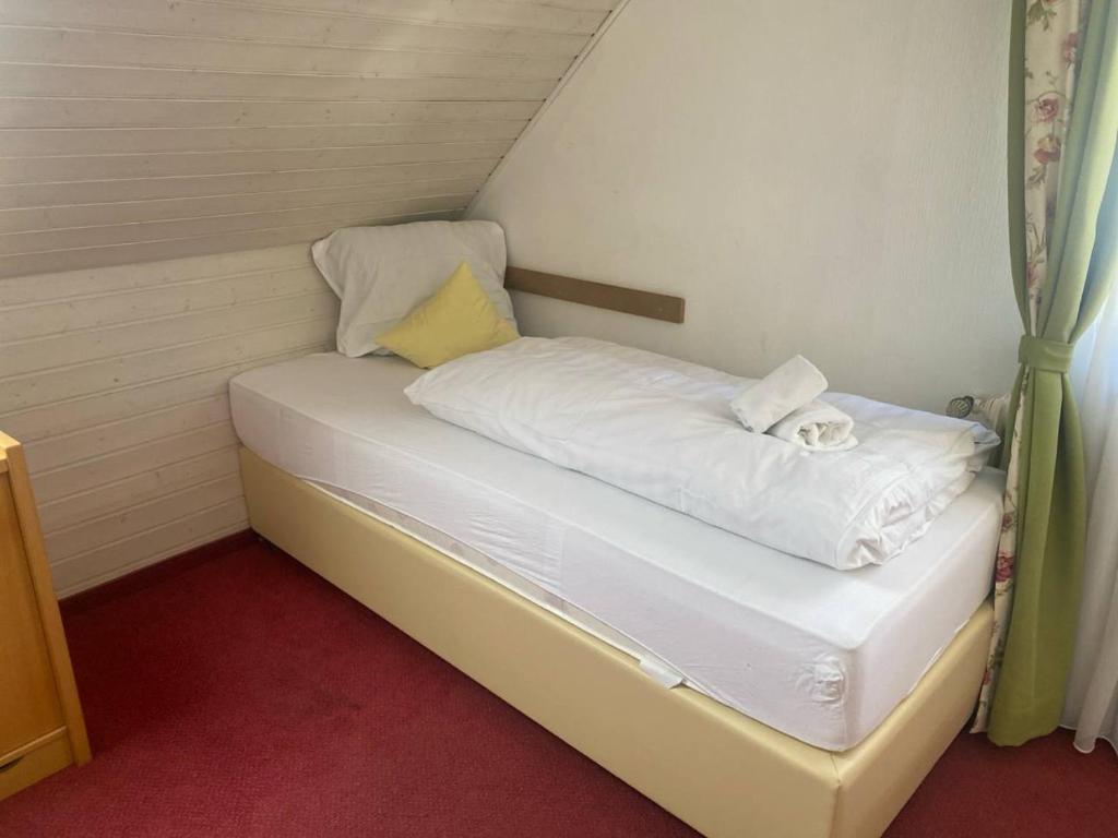 a small white bed with a cat laying on it at Room in Guest room - Single room with shared bathroom and kitchen in Hundsbach in Forbach