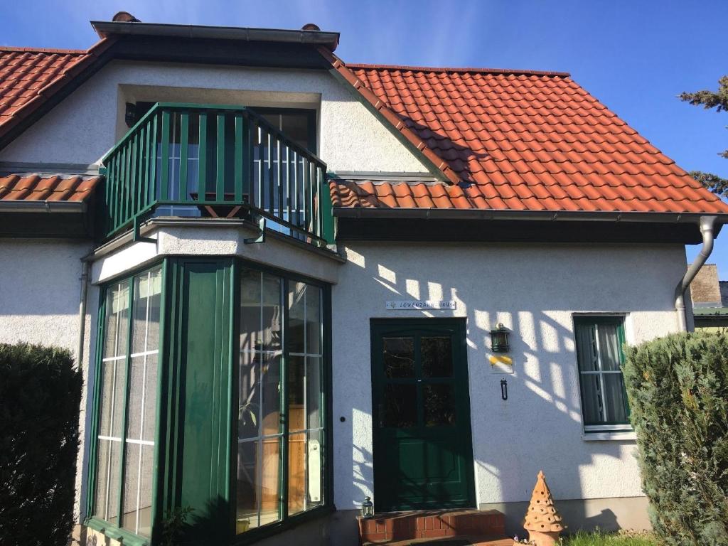 ein Haus mit grüner Tür und rotem Dach in der Unterkunft Ferienhaus mit Gästezimmer für sechs Erwachsene und einem Kind bis sechs Jahre mit Terrasse und Garten in Zehdenick