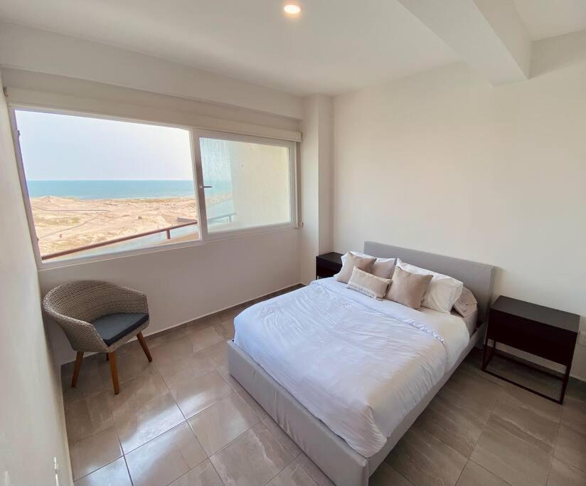 a bedroom with a bed and a large window at Depto con alberca y Netflix condominio in Conchal