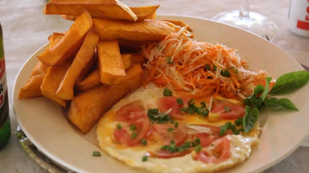 a plate of food with an omelet and french fries at White Beach Bungalow & Restaurant in Lénakel