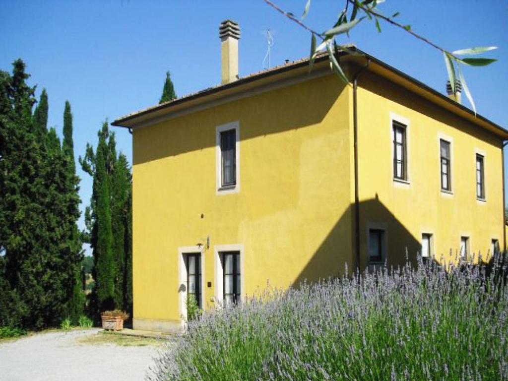 ein gelbes Haus mit einem Kamin darüber in der Unterkunft Belvilla by OYO Casale Nuovo in Chianciano Terme