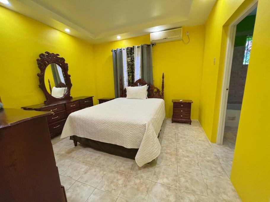 Dormitorio amarillo con cama y espejo en Boscobel Hillside Hideaway, en Saint Mary
