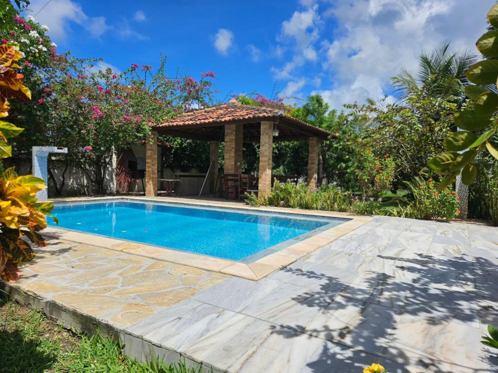 a swimming pool in a backyard with a gazebo at Refúgio das bouganvillea in Igarassu