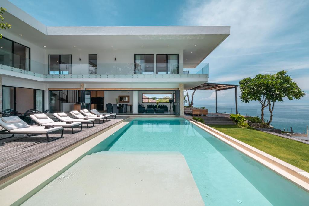 Villa Namaskar - Iconic 5BR Cliff Top Villa - 180° Ocean View في جيمباران: بيت فيه مسبح وبلكونه