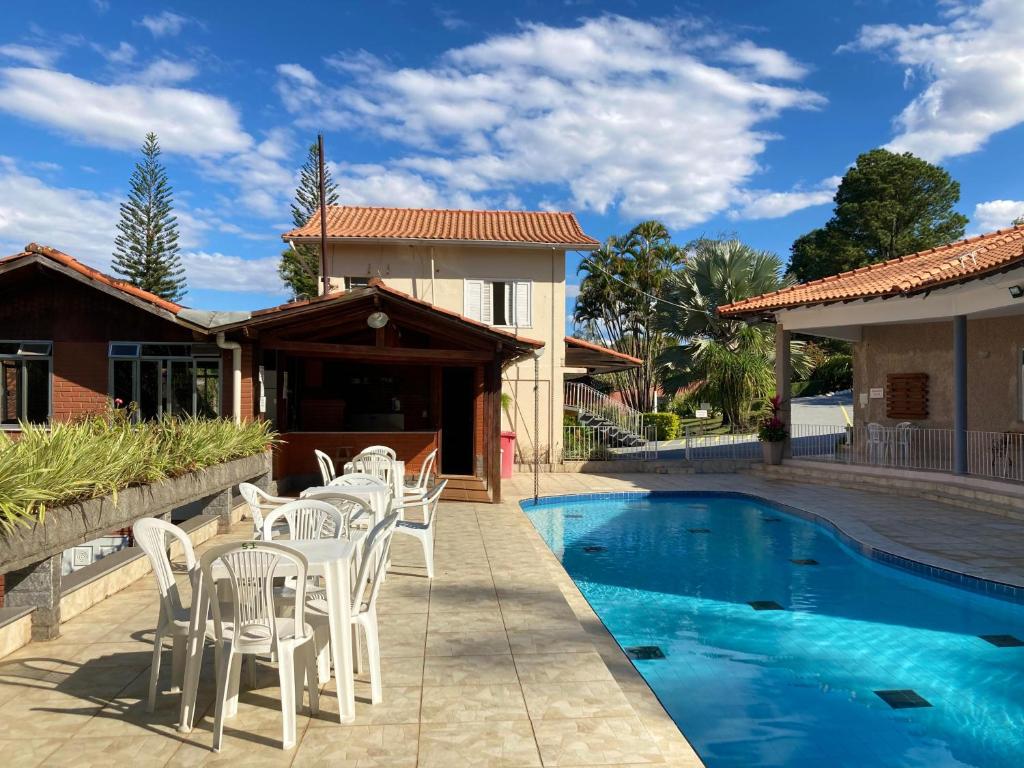 a patio with white chairs and a swimming pool at Pousada Vale das Flores in Penedo
