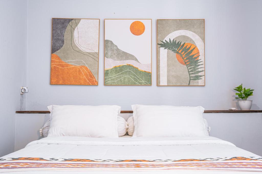 a bedroom with three paintings above a bed at Brownies House in Bandung