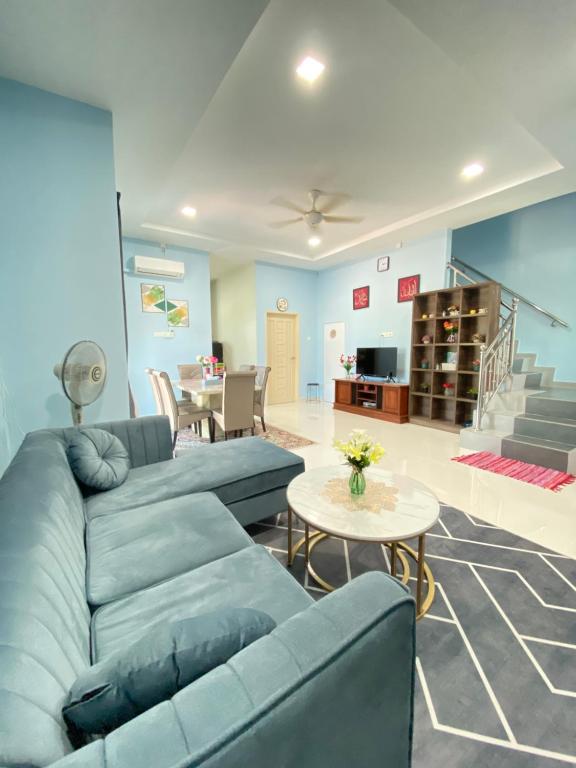 a living room with a blue couch and a table at HOMESTAY ACIK in Kampong Tanjong Gelam
