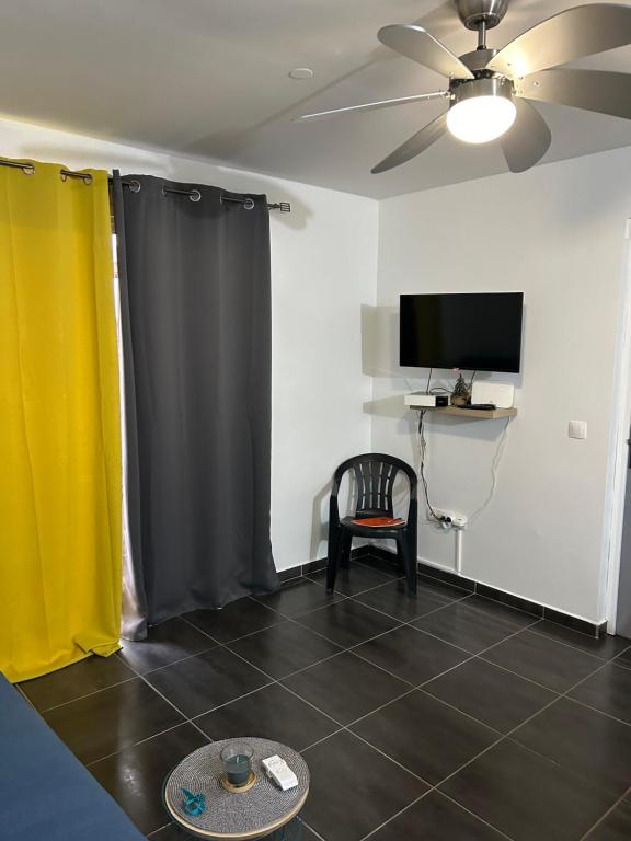 a living room with curtains and a chair and a tv at KARAPAT in Le Gosier