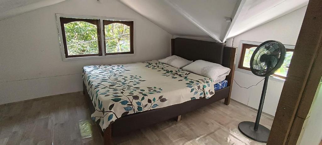 um quarto com uma cama e uma ventoinha. em Jorge & Pony House 2 em El Nido