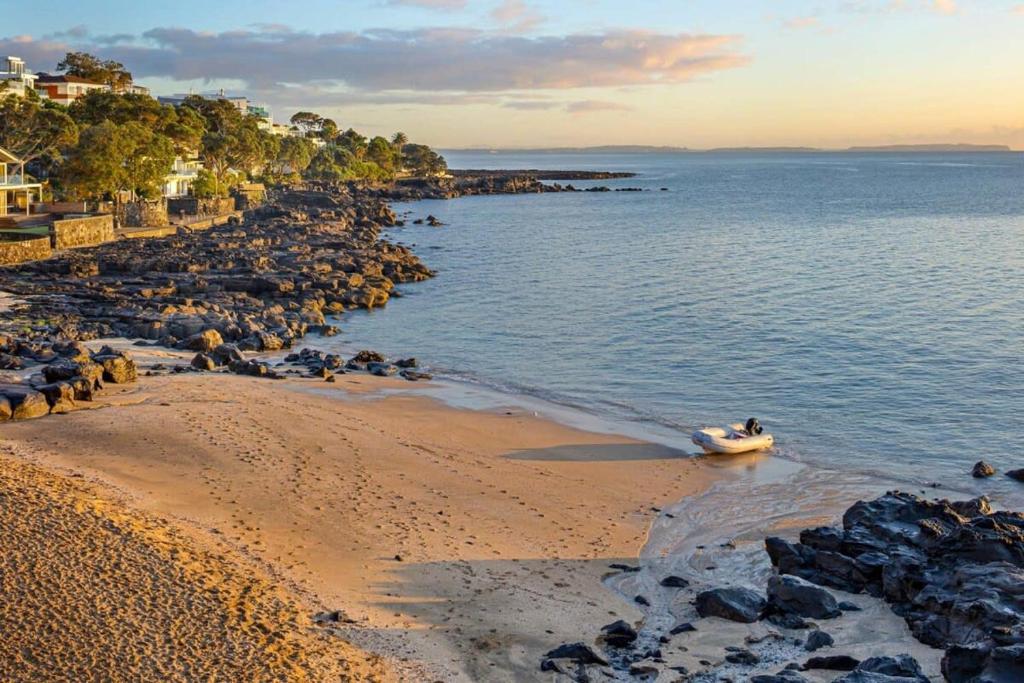un barco en el agua en una playa en Takapuna Beachfront w Stunning Views, en Auckland