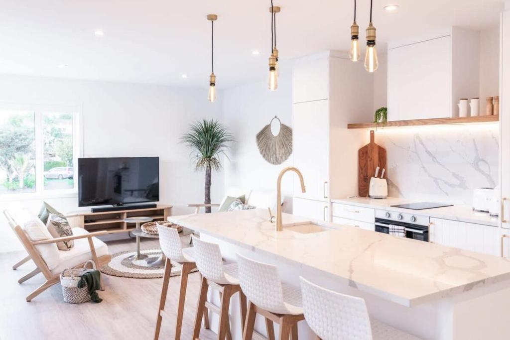 a white kitchen with a large island in the middle at Luxury Apart, Seaviews & Balcony, Full Kitchen & Heat Pump in Auckland