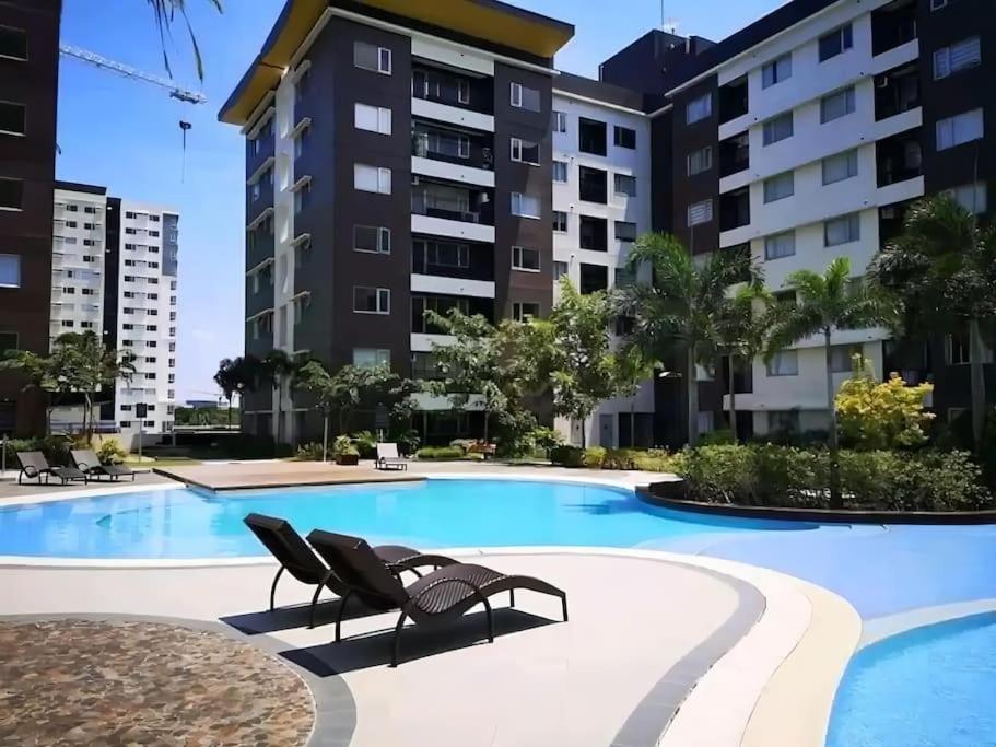 a swimming pool with two lounge chairs in front of a building at Elegant 2 Bedroom Unit @Avida#27 in Iloilo City