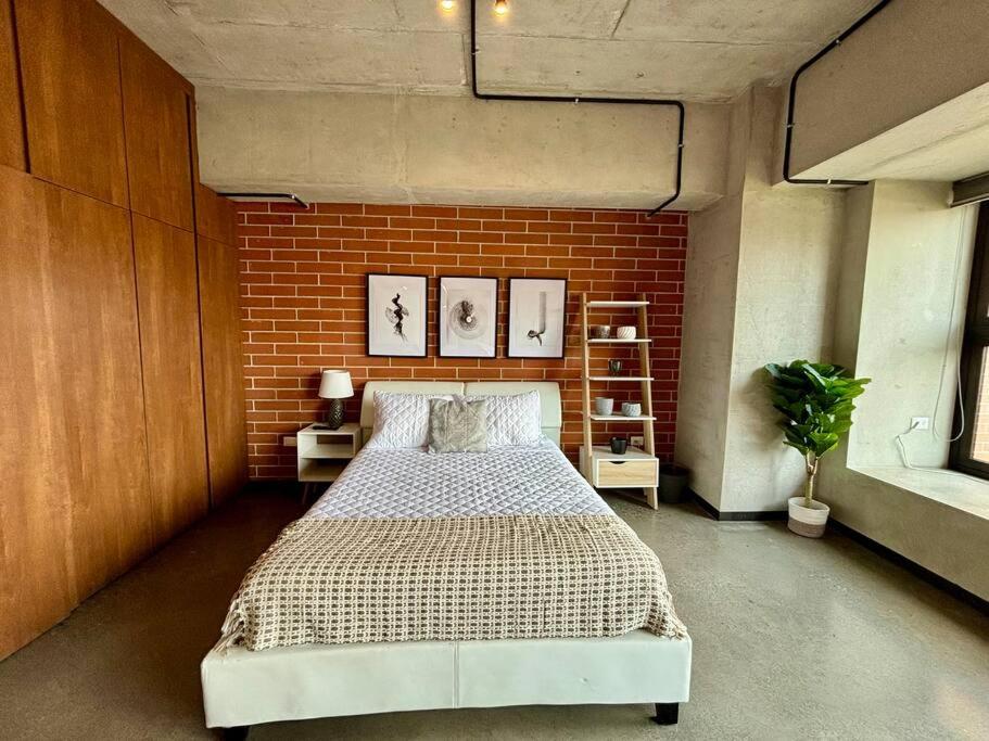 a bedroom with a large bed in a brick wall at Artistic Apartment in Zone 4 in Guatemala