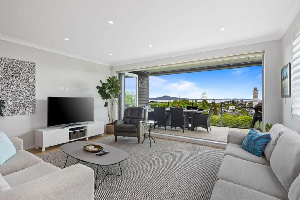 uma sala de estar com um sofá e uma televisão em Ocean View Spacious 5BR Retreat for Families em Auckland