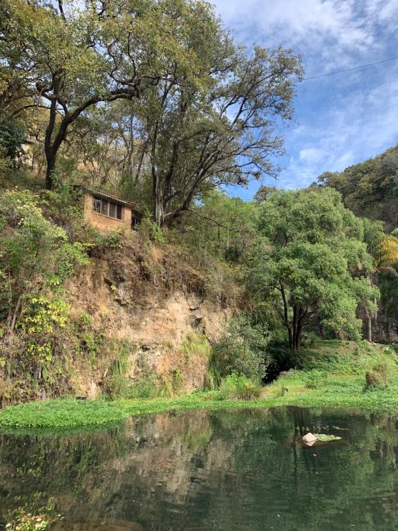 a house on a hill next to a body of water at Cabaña Mi Pequeño Paraíso in Cuernavaca