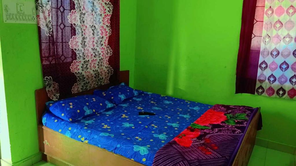ein Schlafzimmer mit einem Bett mit einer grünen Wand in der Unterkunft On Hill Rooms in Yercaud