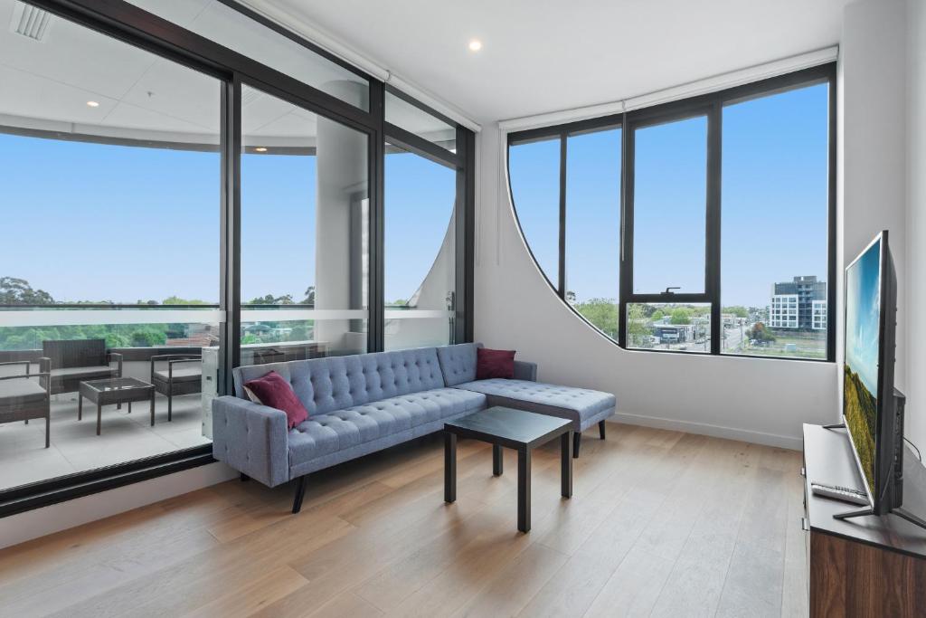 sala de estar con sofá y algunas ventanas en Generous 2-Bed Apartment with Great Amenities, en Melbourne