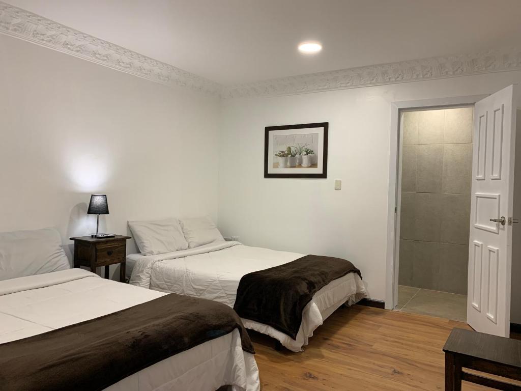 een slaapkamer met 2 bedden en een schuifdeur bij NASS Bed & Breakfast in Cuenca