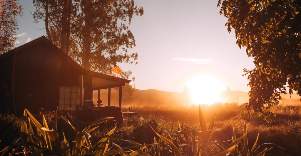 una casa in un campo con il tramonto di Fiery Peak Eco-Retreat a Geraldine