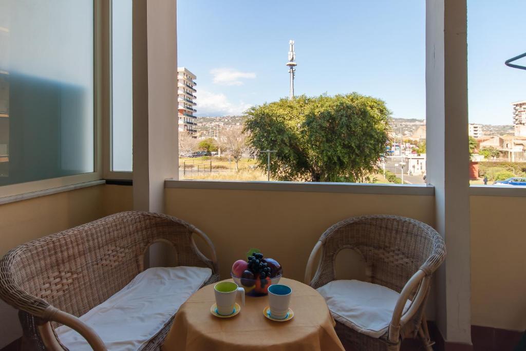 een kamer met 2 stoelen, een tafel en een raam bij Happy Apartment Nettuno Close To Sea - Happy Rentals in Catania