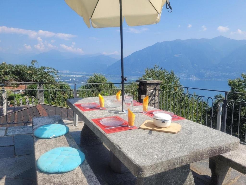 a picnic table with an umbrella and a view at Casa Moorea - b44923 in Brione sopra Minusio