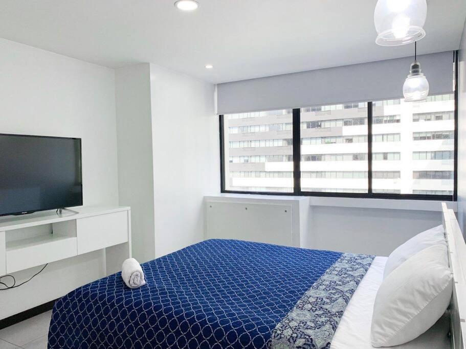 ein Schlafzimmer mit einem blauen Bett und einem TV in der Unterkunft ¡Hermosa vista al río! Piso alto in Guayaquil