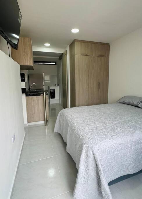 a bedroom with a white bed and a kitchen at Loft con aire acondicionado in Florencia