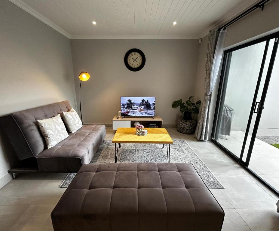 uma sala de estar com um sofá e uma mesa em Affordable Luxury Apartment em Gqeberha