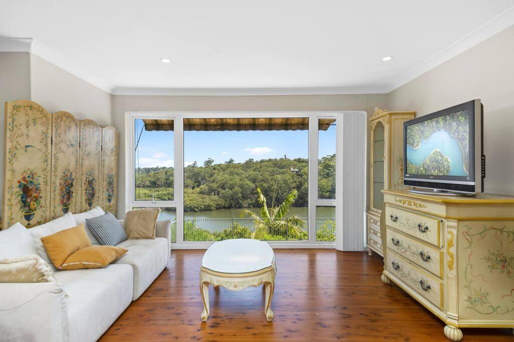 シドニーにあるRiver View Oasis: Spacious 3-Bed House with Poolのリビングルーム(ソファ、テレビ付)