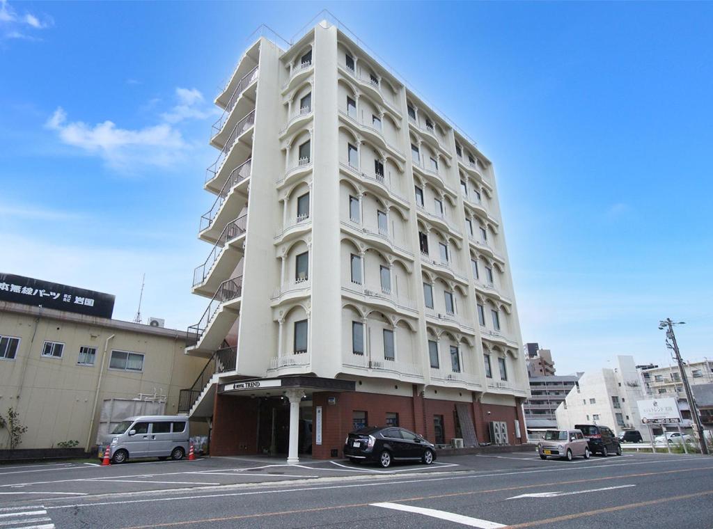 a white building with cars parked in a parking lot at Hotel Trend Iwakuni in Iwakuni