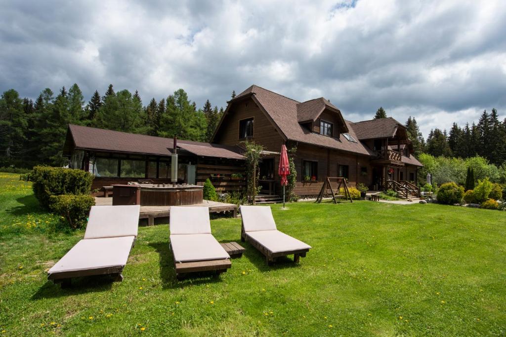 a group of chairs and a table and a house at Penzion Sileo in Pribylina