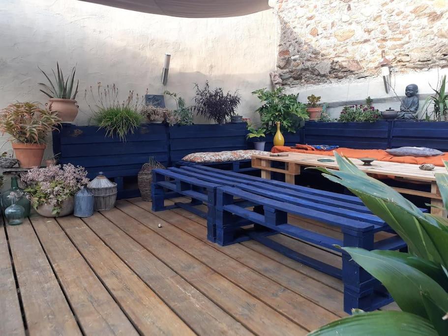 une terrasse avec bancs bleus, table et plantes en pot dans l'établissement Maison de village atypique en bordure de forêt, à Corbère