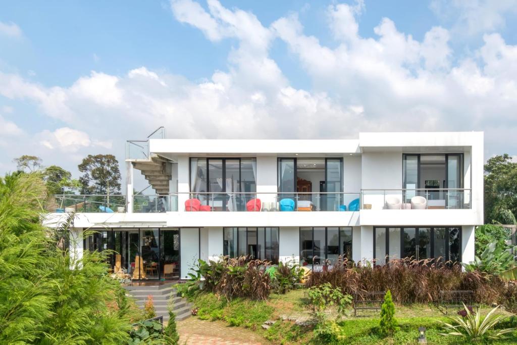 une grande maison blanche avec des fenêtres en verre dans l'établissement TwoSpaces Living at deRos Resort & Cafe, Bogor, à Ciherangsating