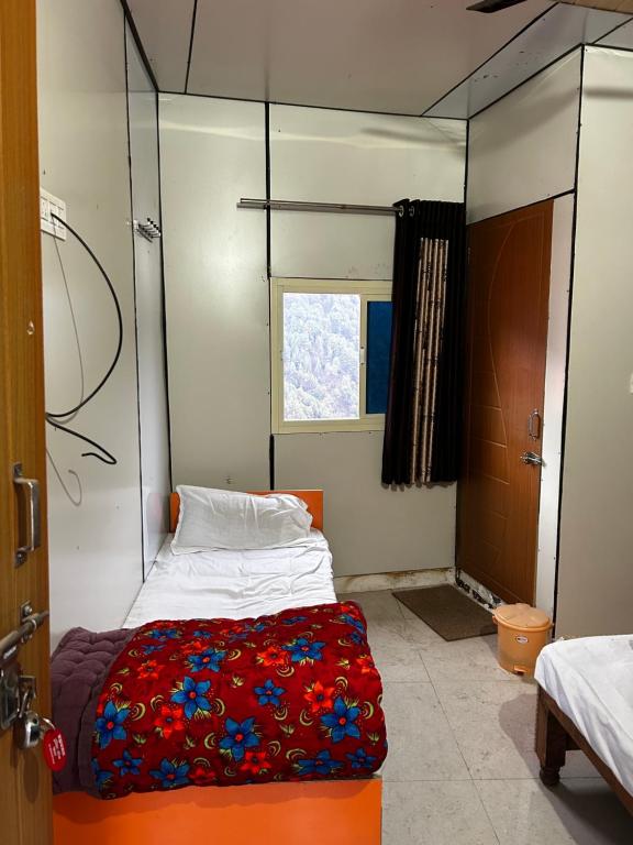 een kleine kamer met een bed en een raam bij Brahma Kamal in Phata