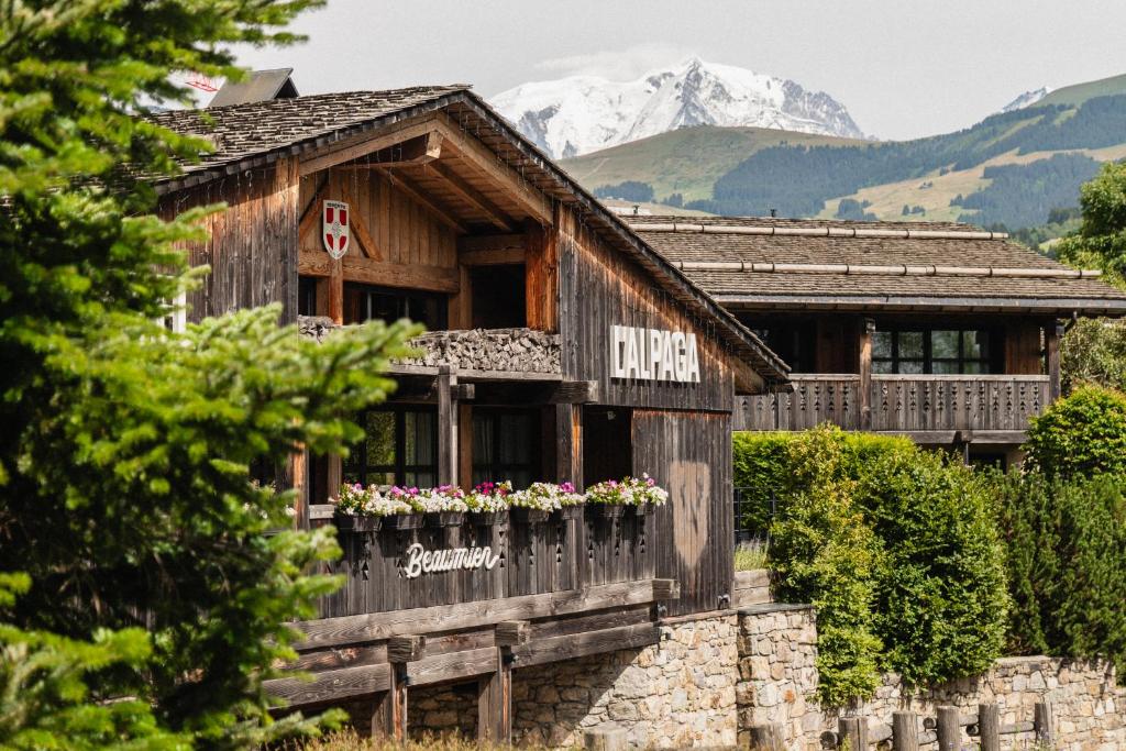 Un bâtiment en bois avec des fleurs dans la fenêtre dans l'établissement L'Alpaga, a Beaumier hotel, à Megève