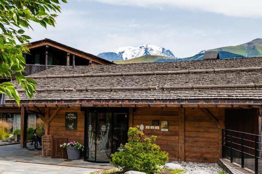 a log cabin with mountains in the background at L'Alpaga, a Beaumier hotel in Megève
