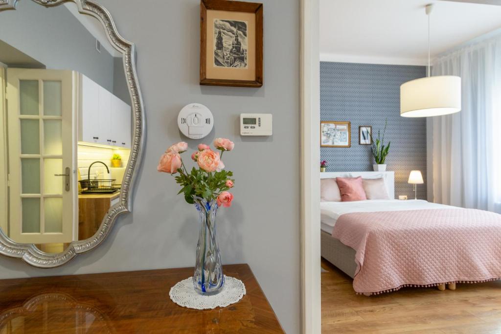 een slaapkamer met een bed en een vaas met bloemen op een tafel bij Smile Apartments Center Kraków Old Town in Krakau