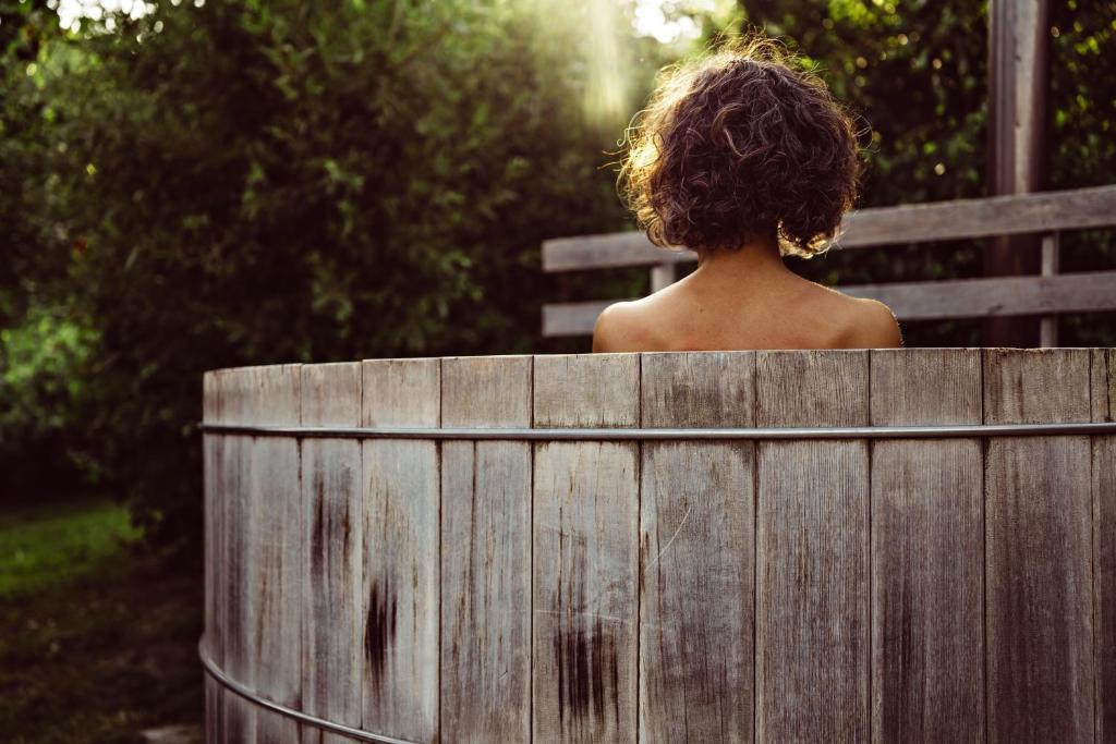 a woman sitting on a bench in a wooden tub at L'Alpaga, a Beaumier hotel in Megève