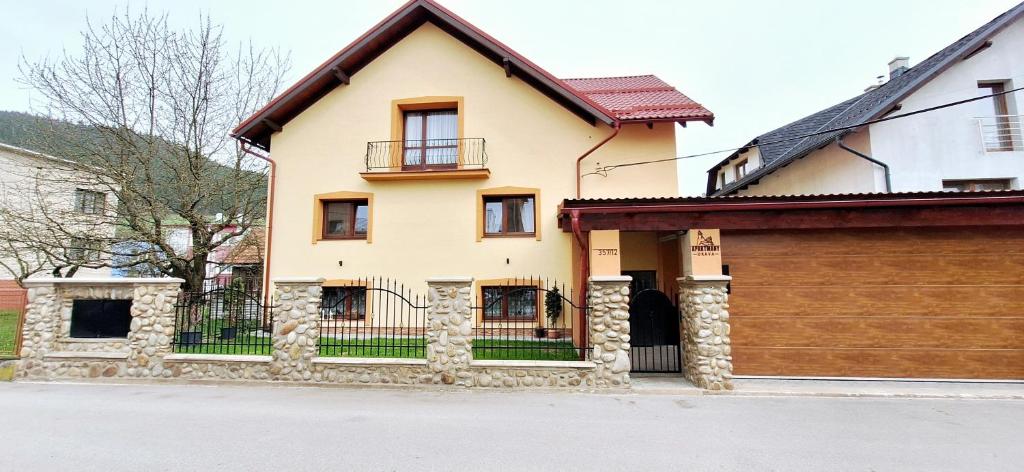 a yellow house with a fence and a garage at Apartmány Orava in Dolný Kubín