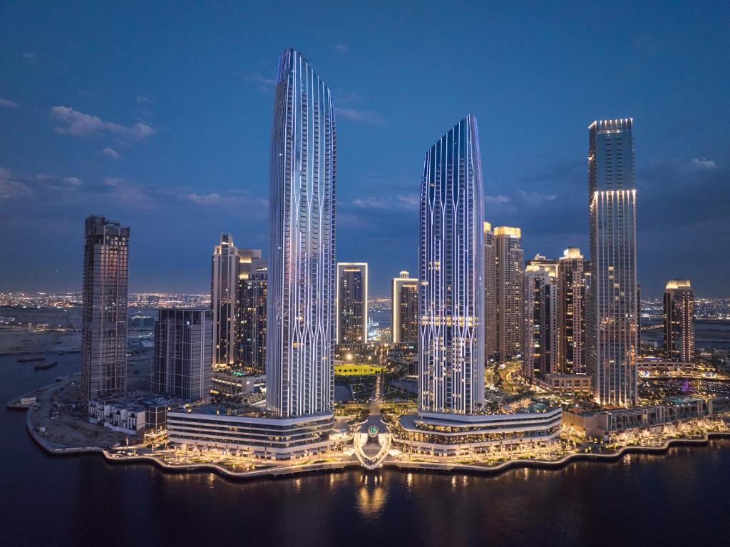 Address Grand Creek Harbour في دبي: أفق المدينة مع ناطحات السحاب الطويلة في الليل