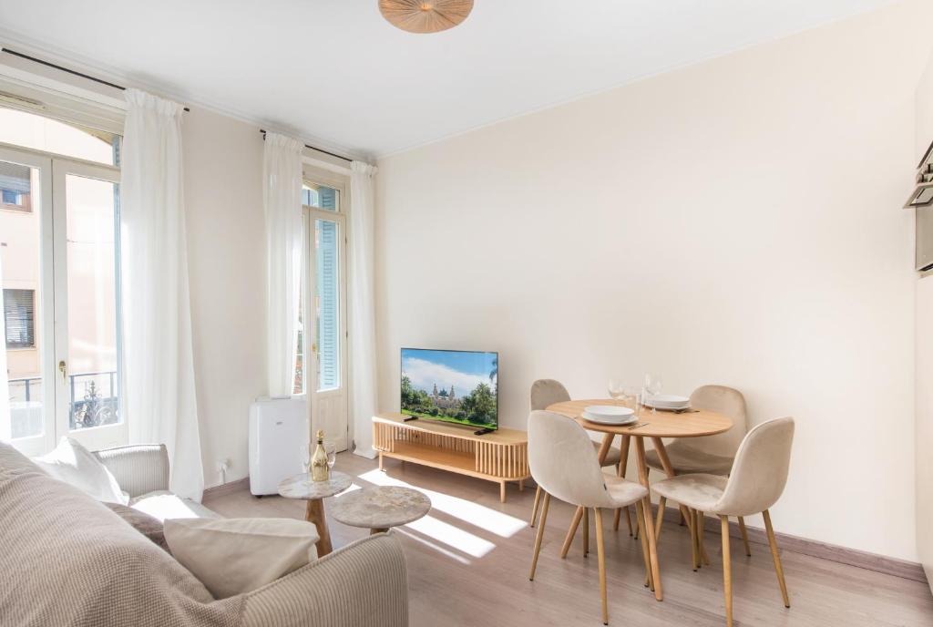 - un salon avec une table, des chaises et une télévision dans l'établissement REPUBLIQUE - Somptueux 2 pièces - 50 mètres de Monaco, à Beausoleil