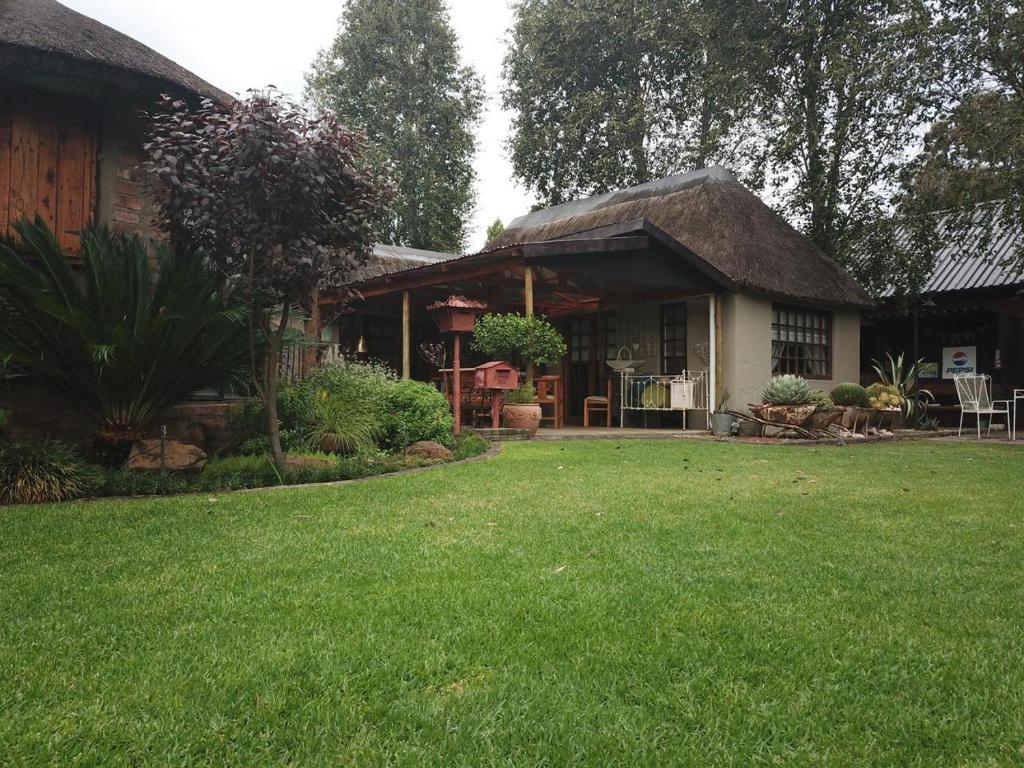 a house with a thatched roof and a yard at Oudam Overnight Accomodation in Bloemfontein