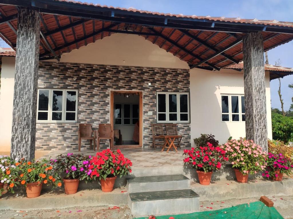 une maison avec des fleurs devant elle dans l'établissement Guddagandi Homestay Sakaleshpura, à Hanbal