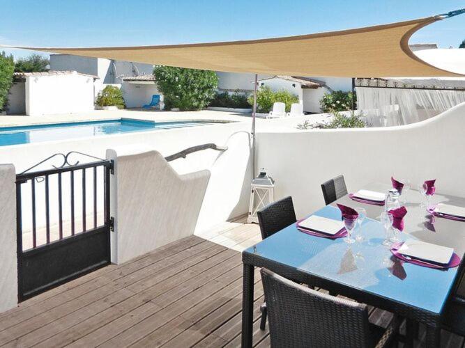 a table with wine glasses on a patio with a pool at Terraced House Saintes-Maries Near Beaches in Saintes-Maries-de-la-Mer