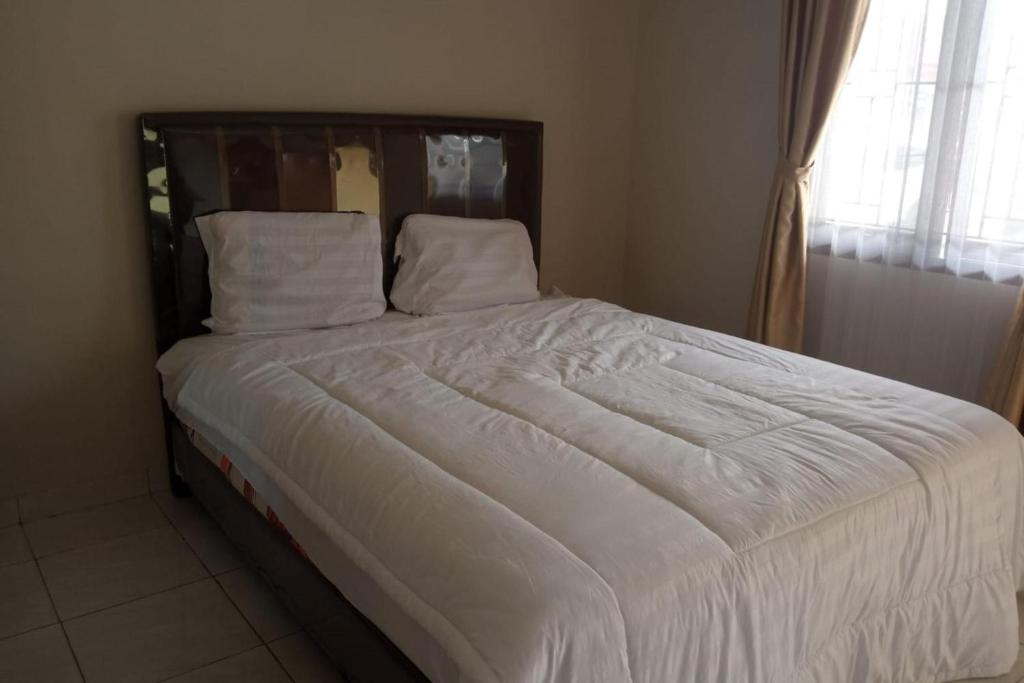 ein Bett mit weißer Bettwäsche und Kissen in einem Schlafzimmer in der Unterkunft OYO 93850 Njy House Syariah in Pekanbaru