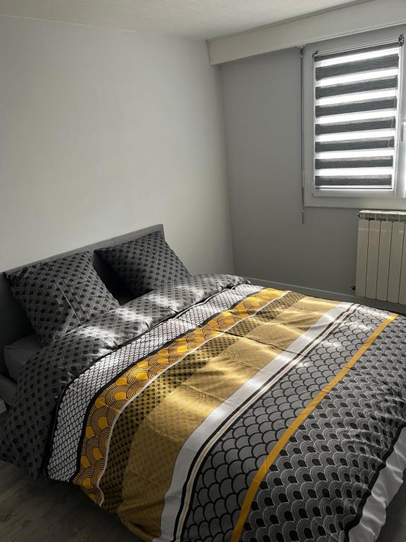 a bedroom with a bed with a black and yellow comforter at Bel appartement de 60 m2 in Rosières-près-Troyes
