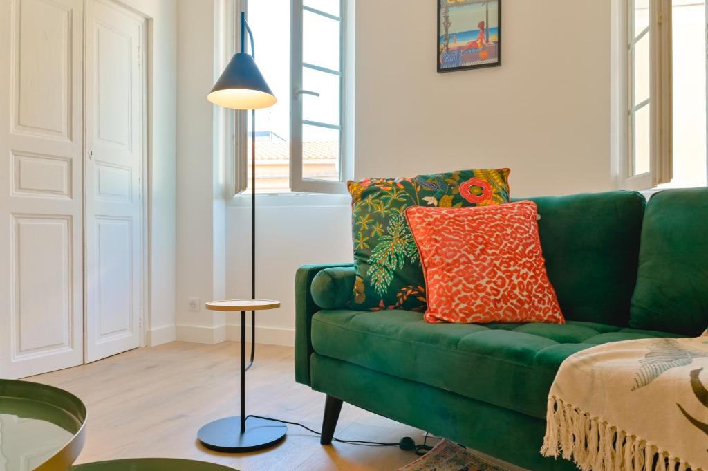 - un canapé vert avec des oreillers colorés dans le salon dans l'établissement Appartement chic & chaleureux - cœur de ville, à Ajaccio