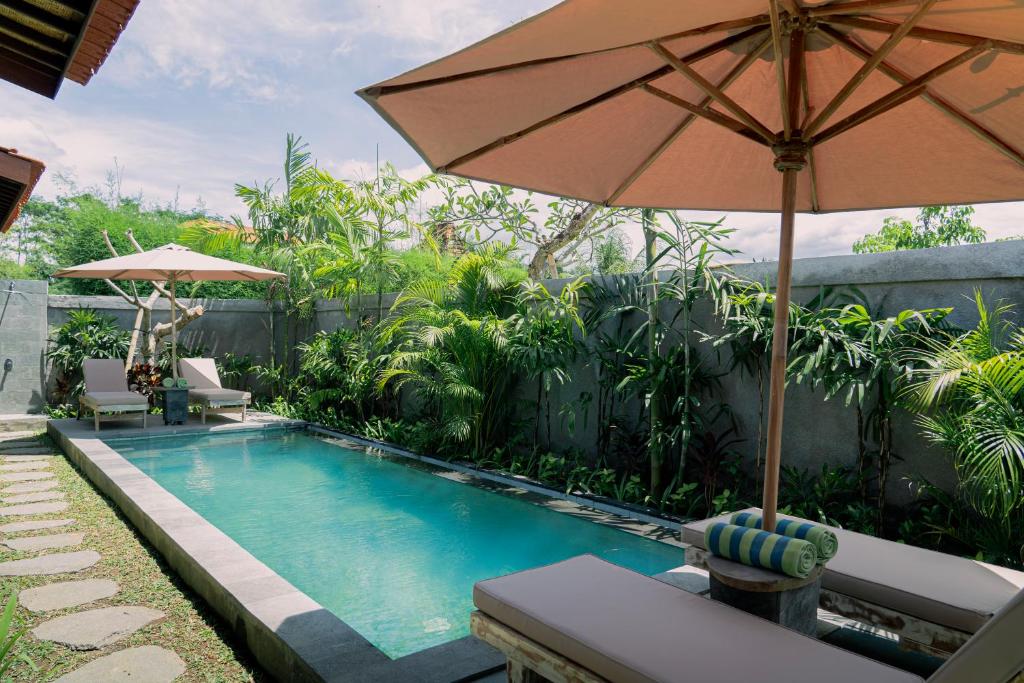una piscina con sombrilla, mesa y sillas en Aswanaya Villas Ubud, en Ubud